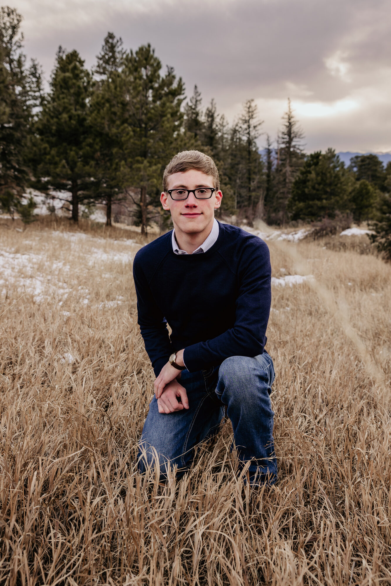 Jacob Citron kneeling in the grass in Colorado - high school senior photos, 2023